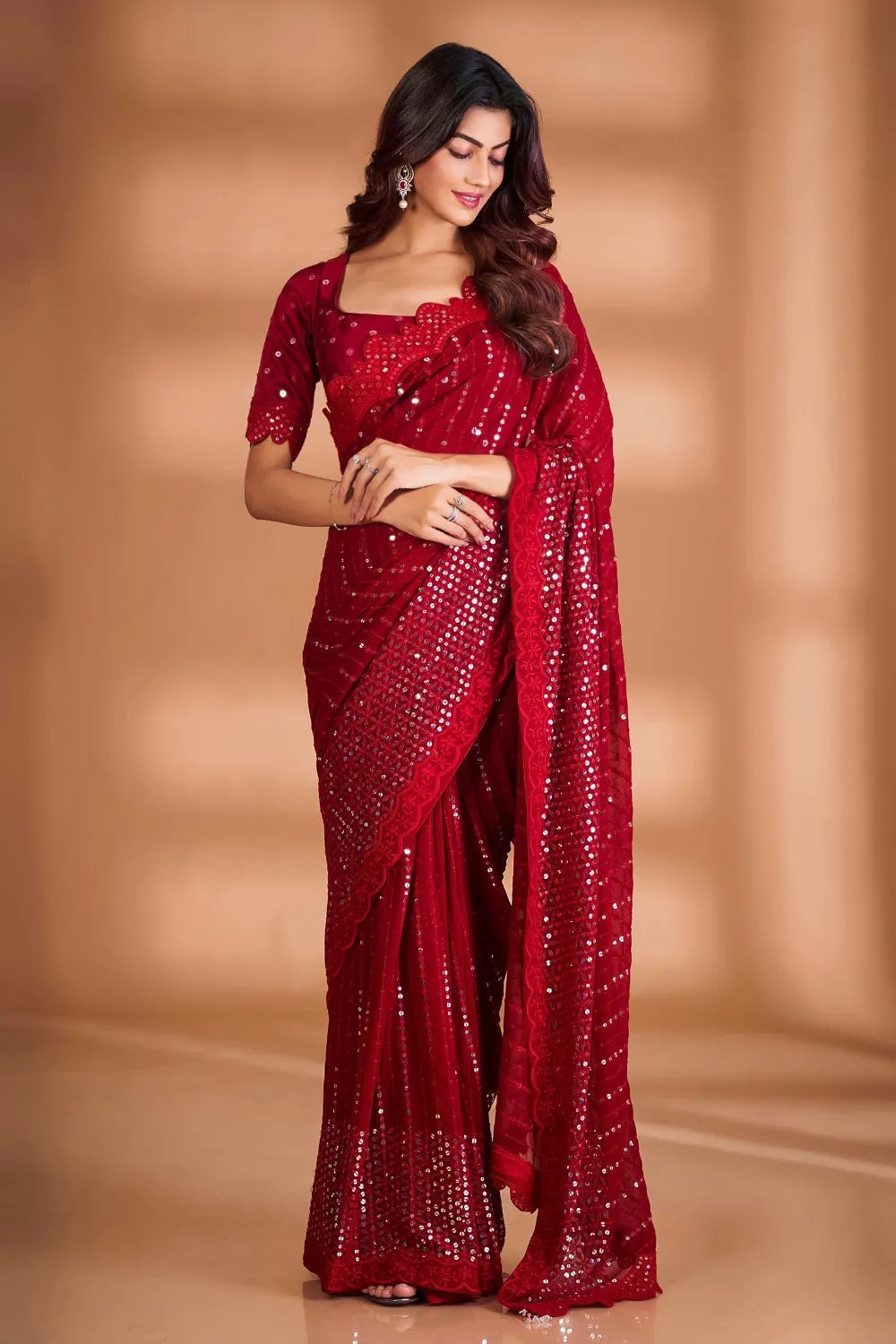 Woman in a red saree with sequin work, scalloped border and a matching square-neck blouse, looking down